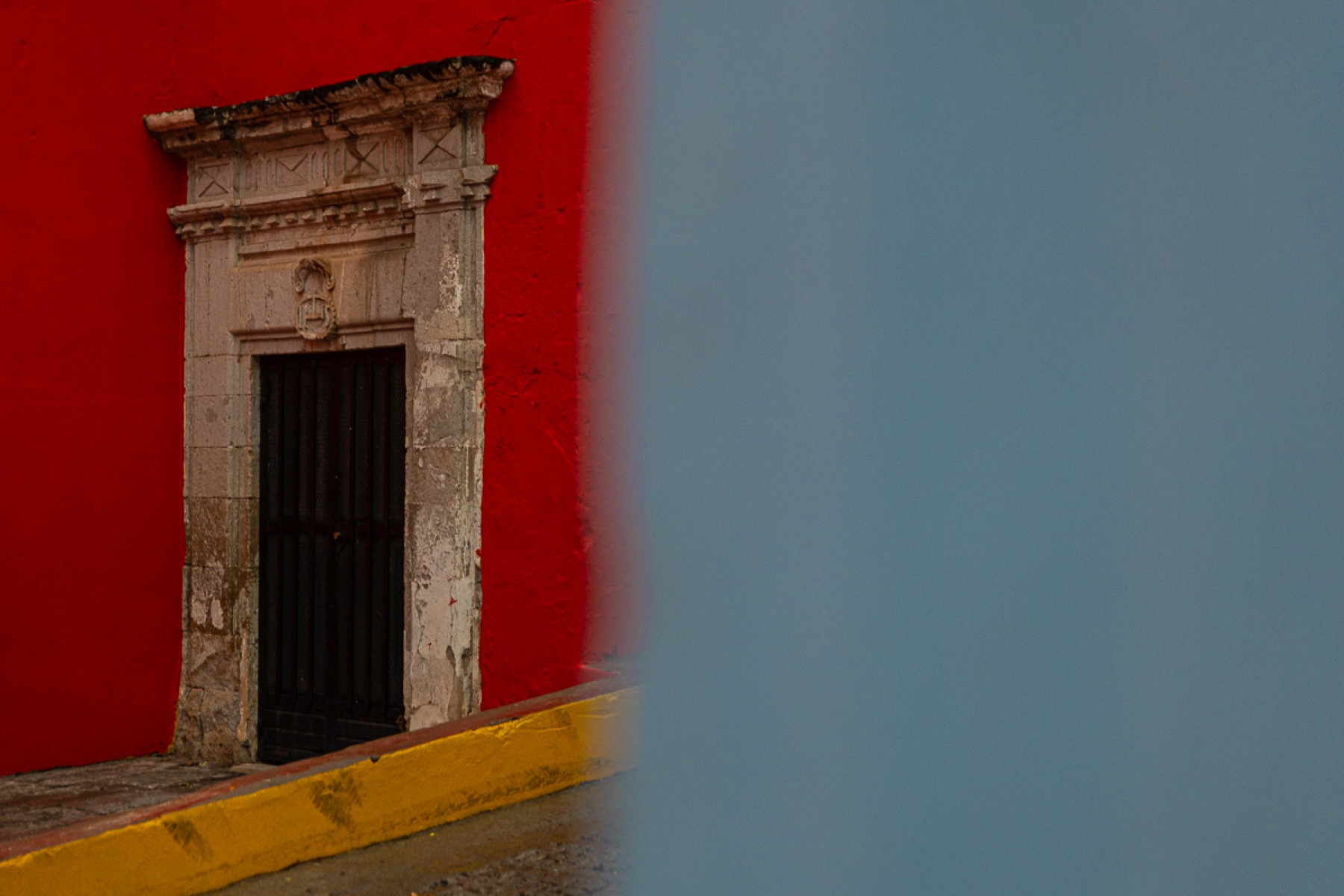 Puerta antigua en muro rojo y plano azul